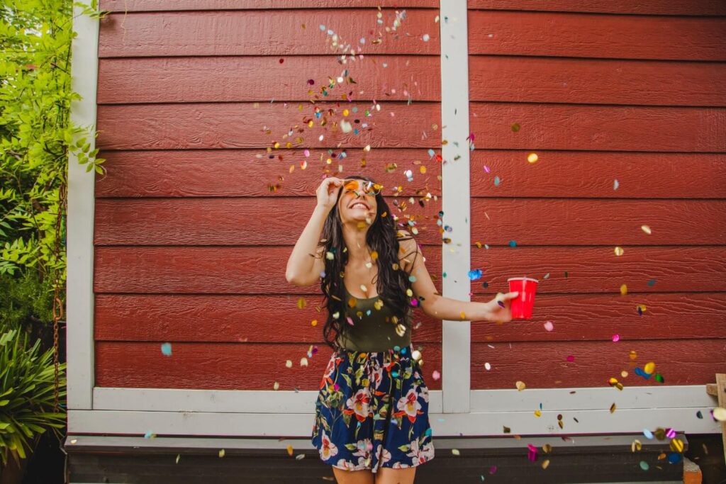 Femme souriante portant une robe élégante et colorée lors d'une fête d'anniversaire avec décoration festive