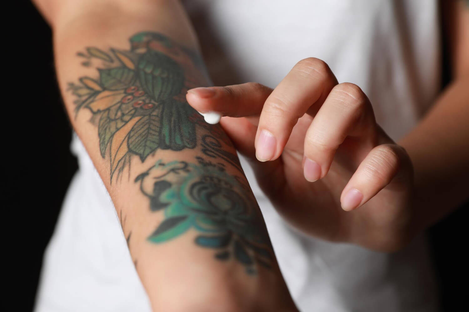 Personne appliquant une crème cicatrisante sur un tatouage récent avec boutons