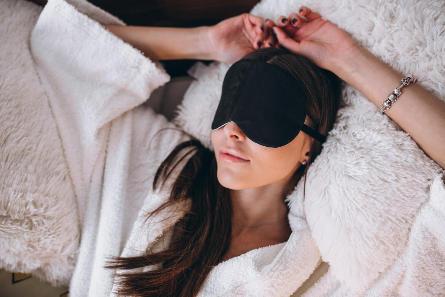 Femme utilisant un masque de sommeil intelligent avec technologies beauty sleep tech dans une chambre moderne équipée d'accessoires connectés pour le sommeil beauté