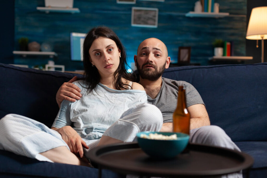 Couple sur un canapé, illustrant le besoin d'espace quand son mari vous touche tout le temps.