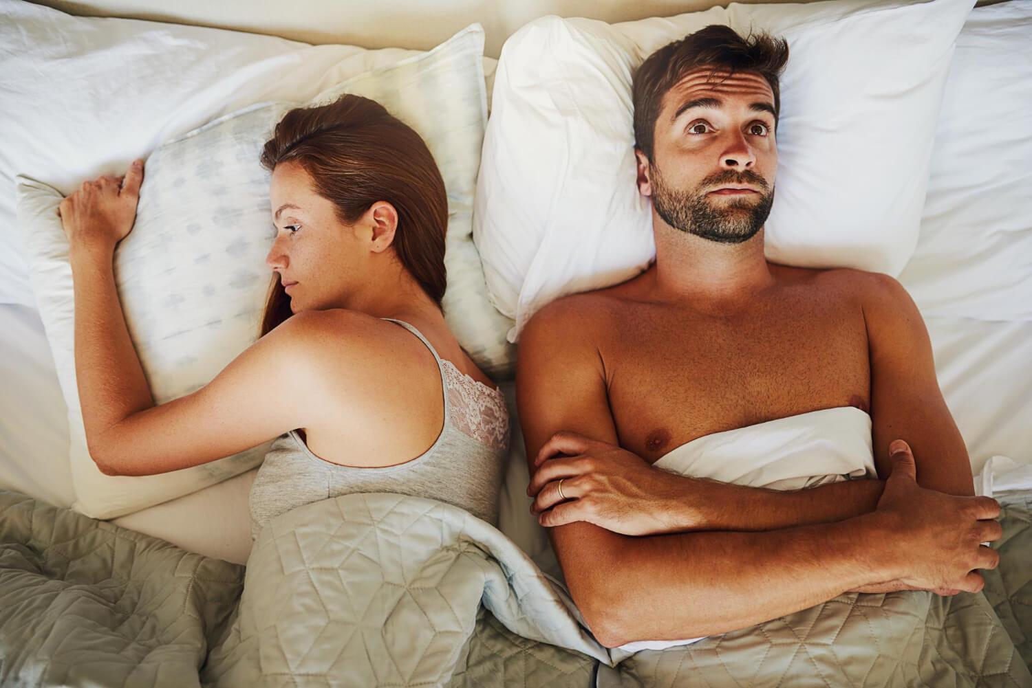 Couple au lit, l'un des partenaires se détourne, illustrant le problème "il ne m'embrasse pas".