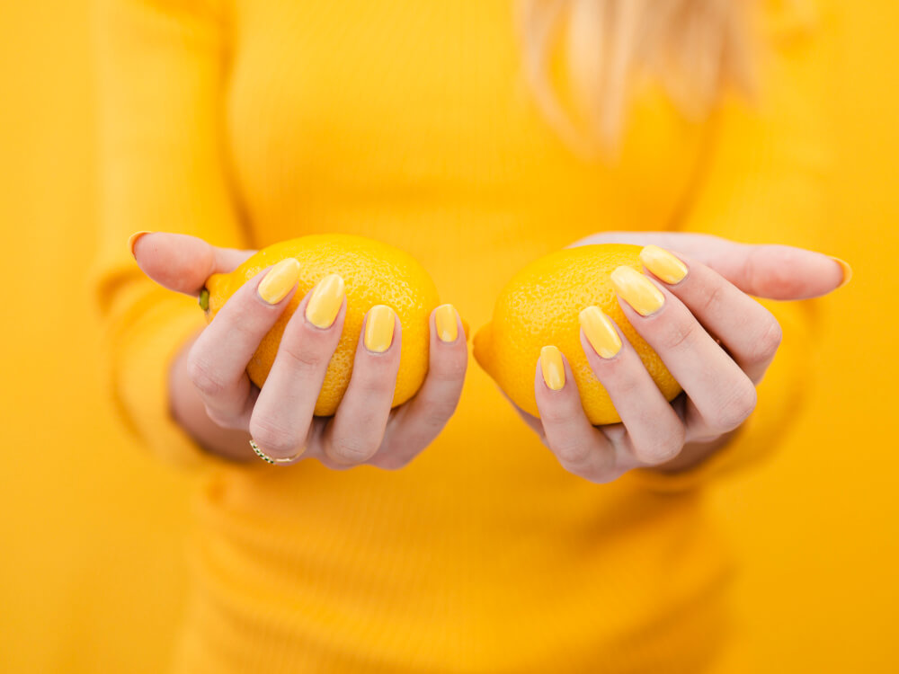 Mains soignées avec des ongles sains, à côté d'un citron.
