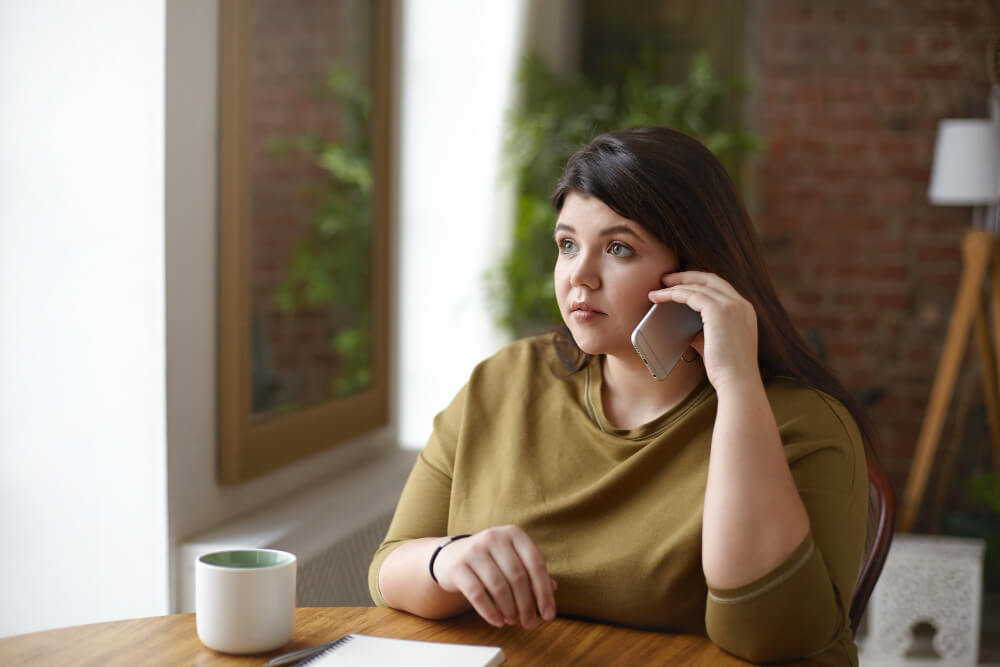 Femme seule attendant devant un téléphone, tandis que son partenaire est occupé ailleurs.