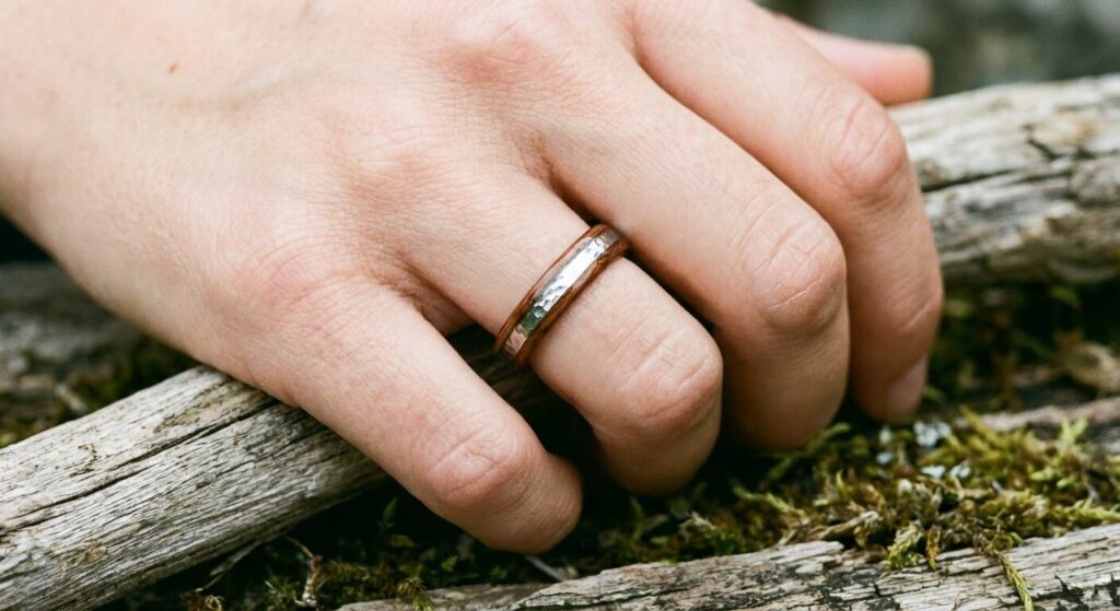 Une main de femme portant une bague fine en bois de santal avec un insert brillant en tungstène.