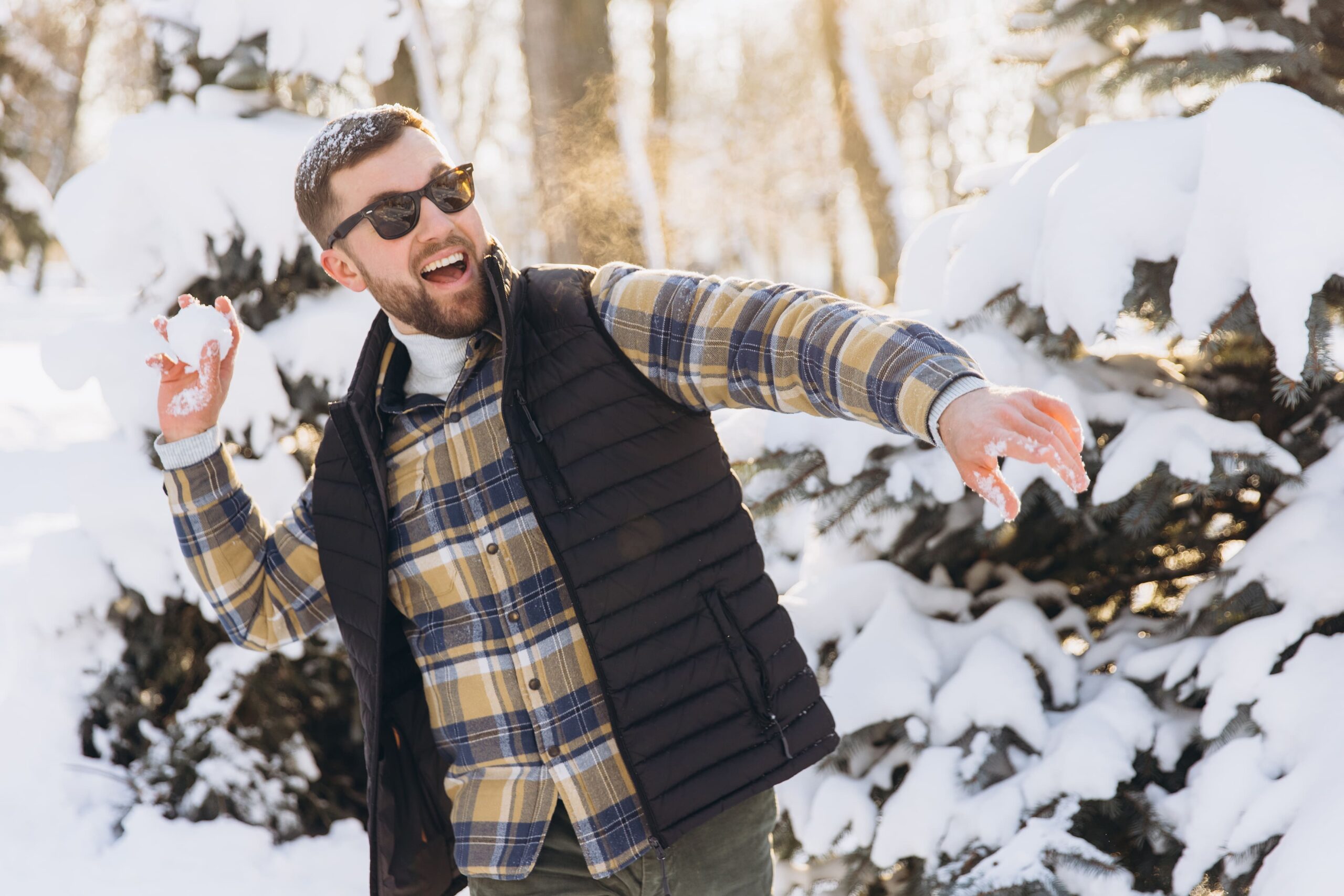 Man playing snowball fight in winter forest enjoying leisure