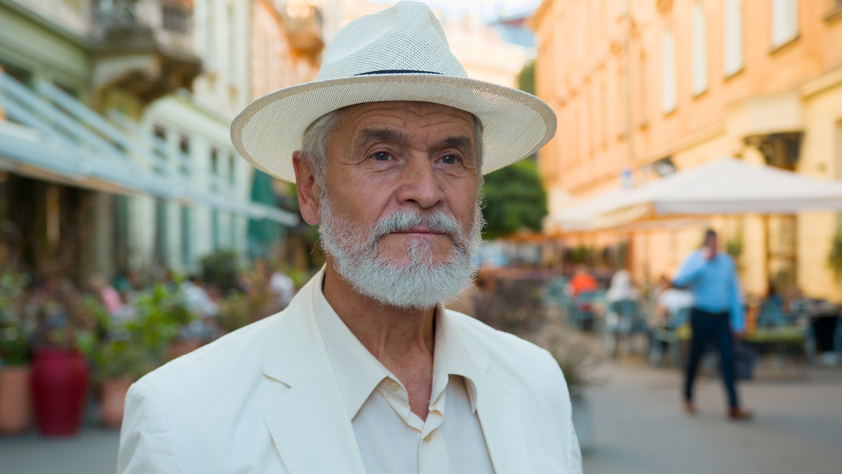 Un homme élégant portant un chapeau de paille de type Panama associé à un costume en lin clair estival.