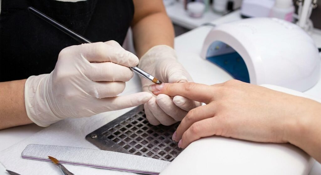 Prothésiste ongulaire corrigeant l'architecture d'un ongle déformé à l'aide d'un gel de construction