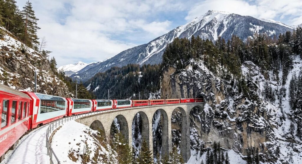 Le train rouge Glacier Express traversant un viaduc enneigé au cœur des Alpes suisses.