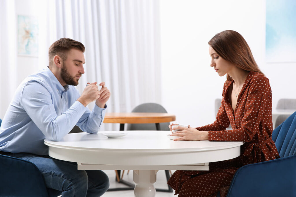 Couple en pleine discussion difficile autour d'une table, tentant de clarifier une situation de séparation