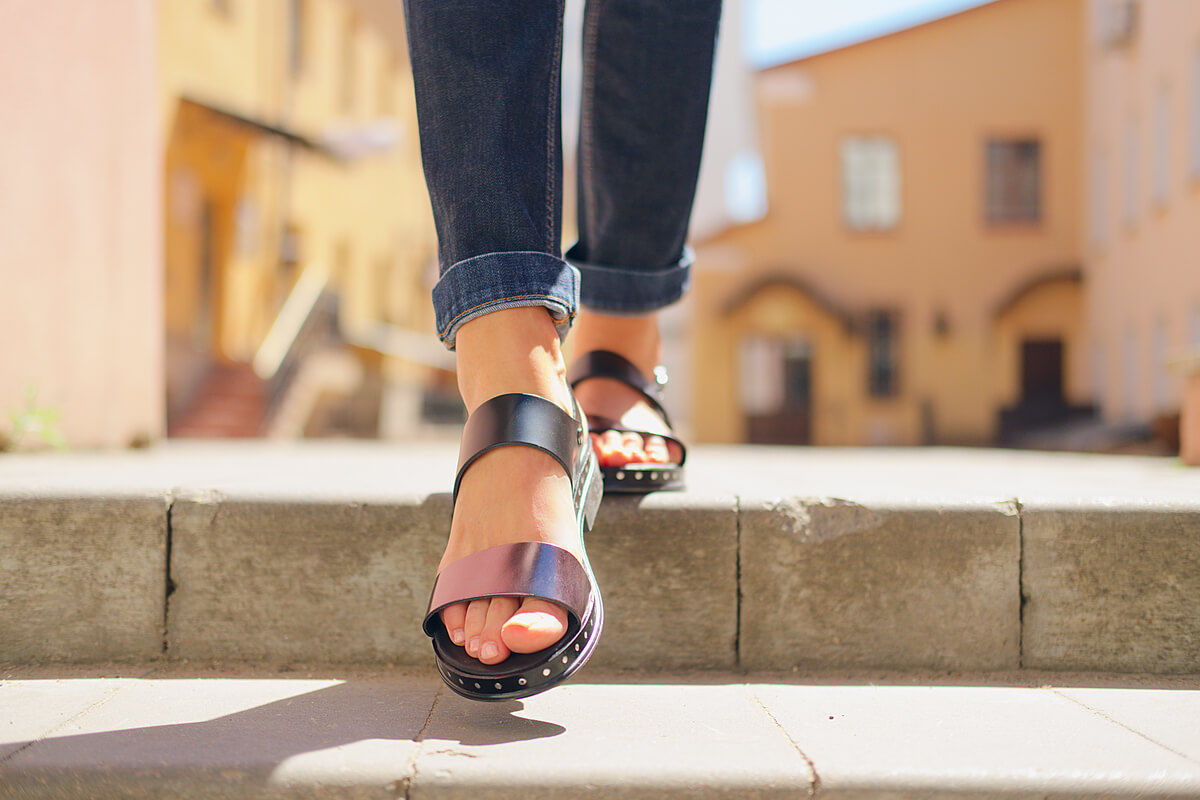 Une personne marchant sur un sentier avec des sandales barefoot légères qui respectent le mouvement naturel du pied.