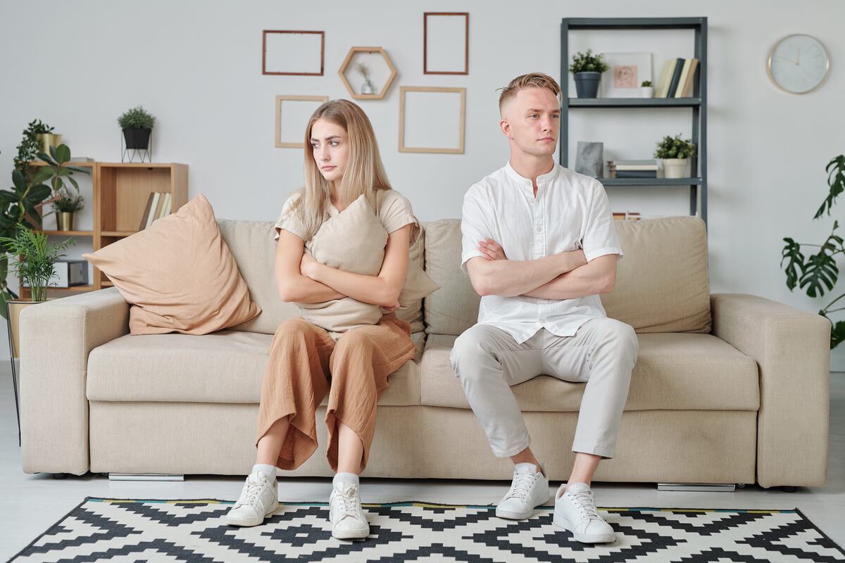 Homme et femme assis aux extrémités opposées d'un canapé, illustrant la distance émotionnelle et l'impasse relationnelle