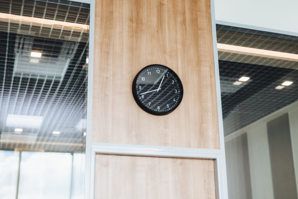 Une horloge murale moderne indiquant la fin des heures de bureau légales en entreprise.