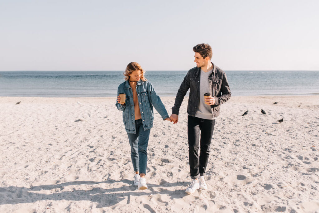 Un homme et une femme se tenant la main en marchant sur la plage, symbolisant la reconstruction des sentiments.