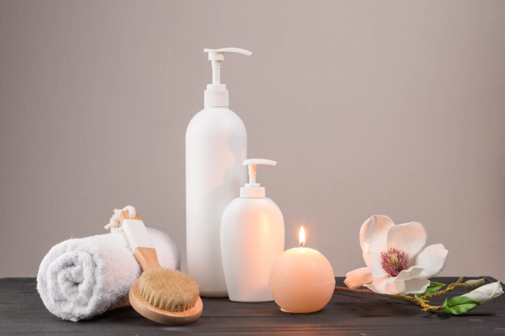 Des produits de soin de douche doux et un flacon de brume corporelle installés au bord d'une baignoire.