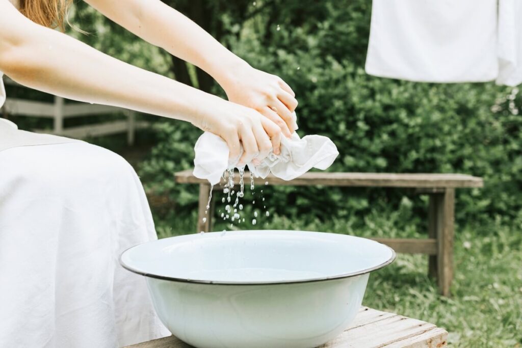Vêtement blanc déteint en rose : comment le rattraper efficacement ? 3 Blanchiment d'un vêtement dans une bassine d'eau chaude contenant des ingrédients naturels d'entretien.