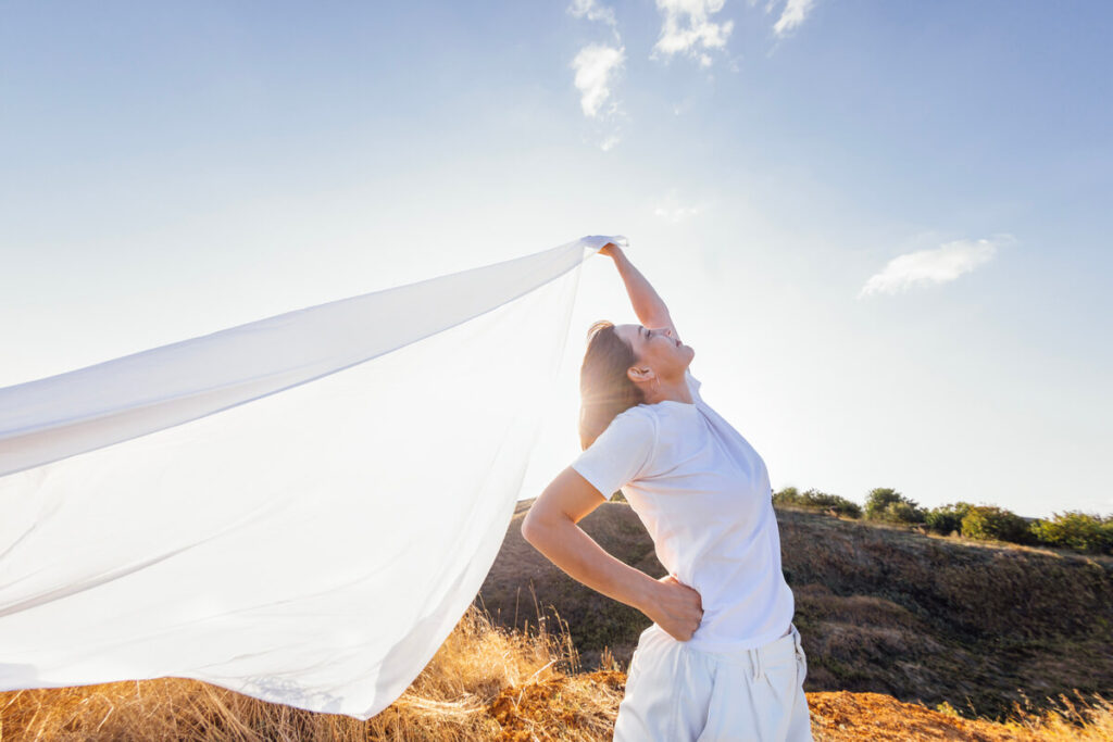 Une robe en mousseline de soie blanche flottant légèrement au vent lors d'un shooting de mode en plein air.