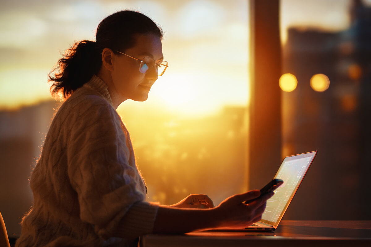 Un employé de bureau éteignant son ordinateur portable alors que le soleil se couche à travers la fenêtre.