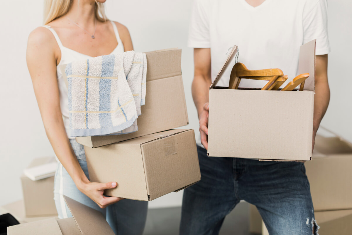 Plusieurs cartons de déménagement remplis de vêtements laissés au milieu d'une pièce après une séparation de couple.