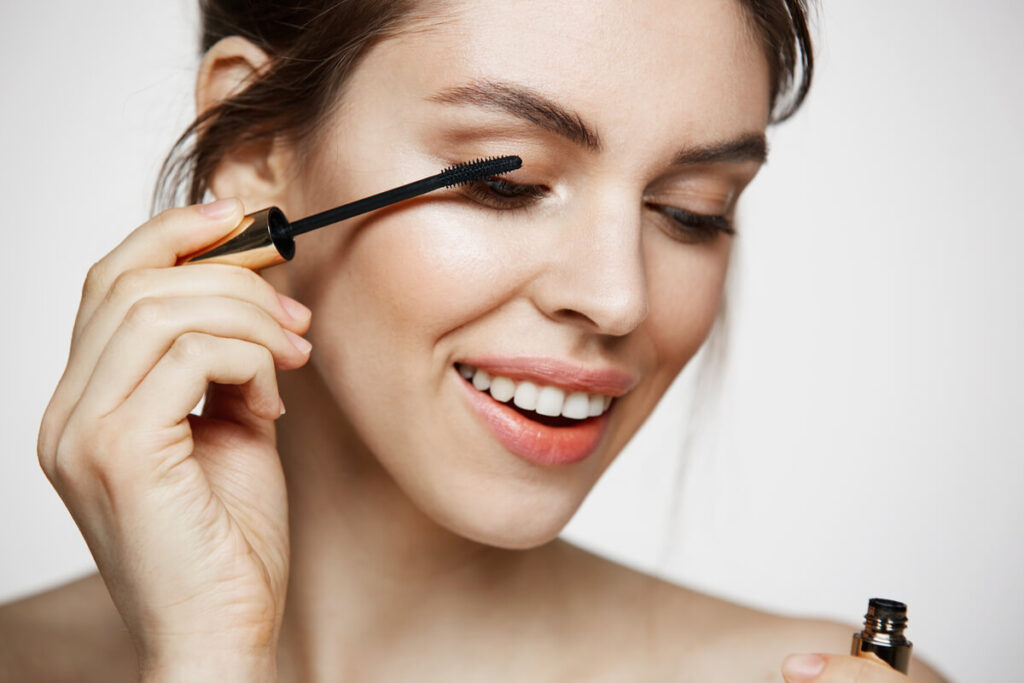 Est-ce que le mascara abîme les cils ? La réponse claire 2 Une femme appliquant délicatement du mascara noir sur ses cils à l'aide d'une brosse applicatrice.