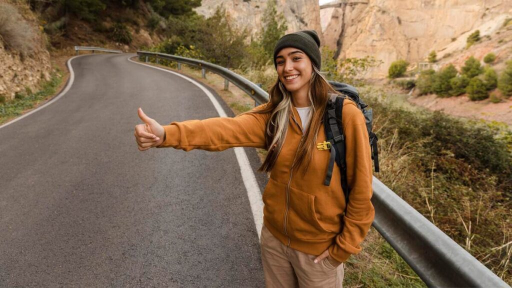 Faire du stop en Espagne : ce qu'il faut savoir avant de se lancer 1 Un voyageur avec son sac à dos levant le pouce au bord d'une route nationale en Espagne.