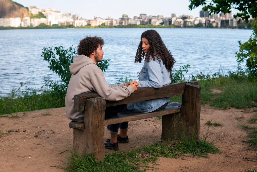 Une femme et un homme discutant sérieusement sur un banc dans un parc.