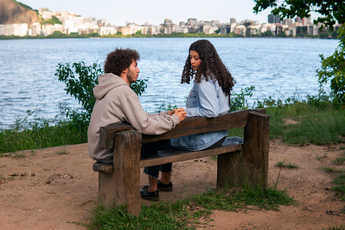 Une femme et un homme discutant sérieusement sur un banc dans un parc.