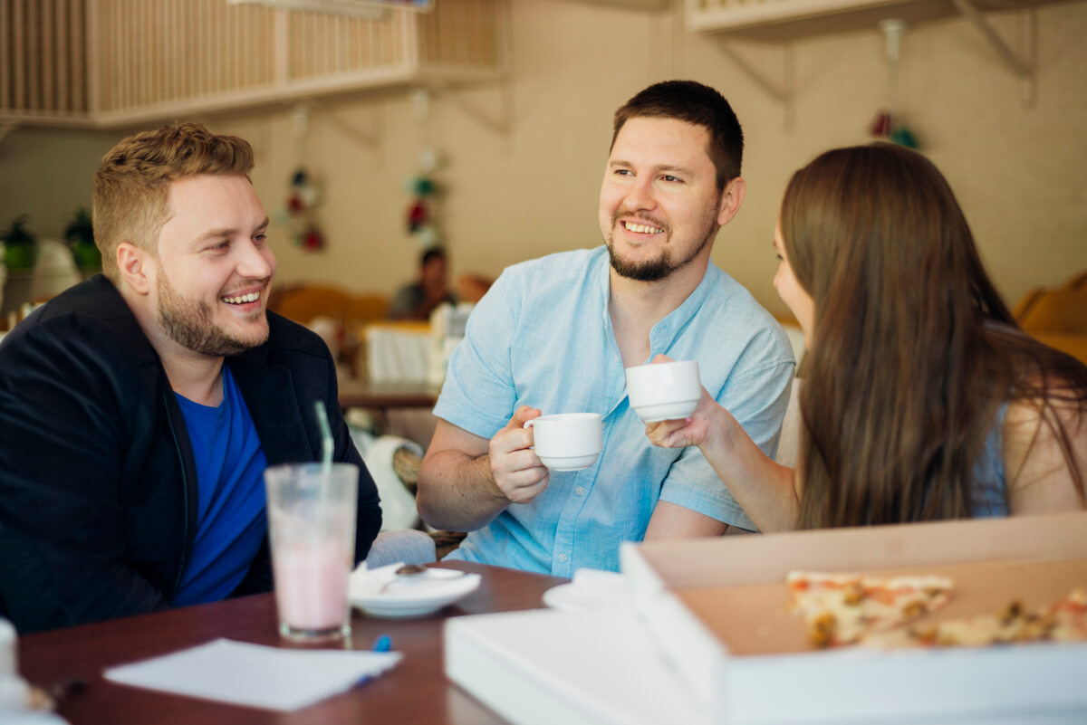 Un homme discutant de manière animée et souriante avec son groupe d'amis dans un café.