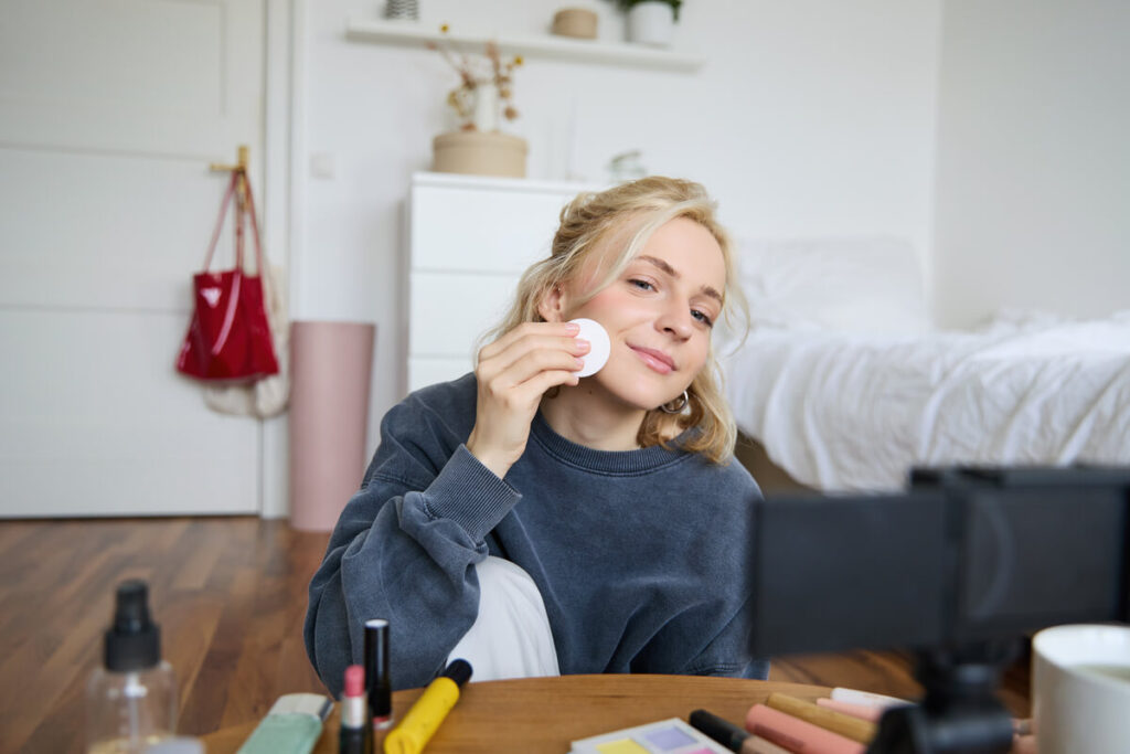 Comment enlever du faux sang sur la peau rapidement et sans irritation ? 2 Une personne nettoyant délicatement son visage avec un coton imbibé d'huile démaquillante après une fête.