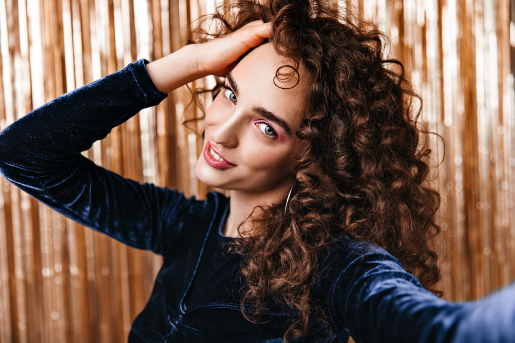 Une femme aux cheveux longs montrant des boucles souples et volumineuses après une permanente.