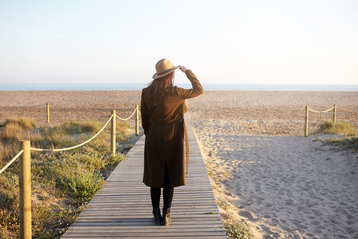 Une personne marchant seule sur une route avec une valise vers l'horizon.