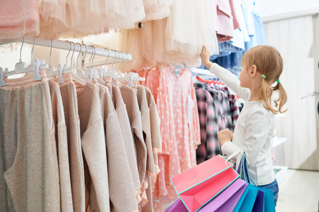 Des vêtements pour enfants alignés sur des cintres dans une boutique de mode pour petits.