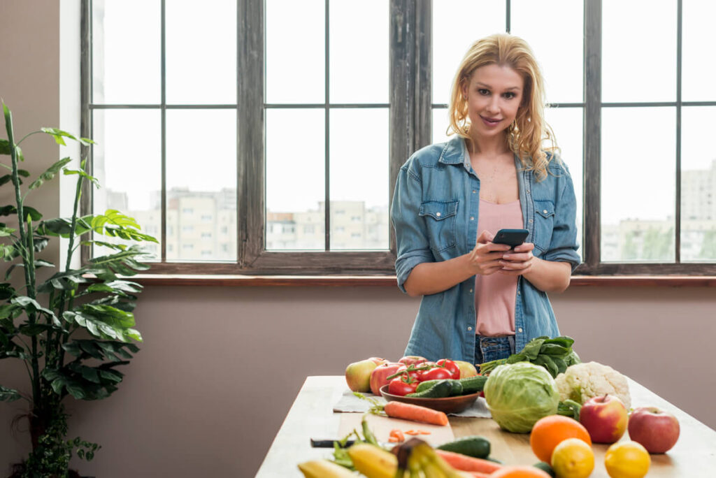 Une personne préparant sa liste de courses en ligne sur une application mobile depuis son domicile.