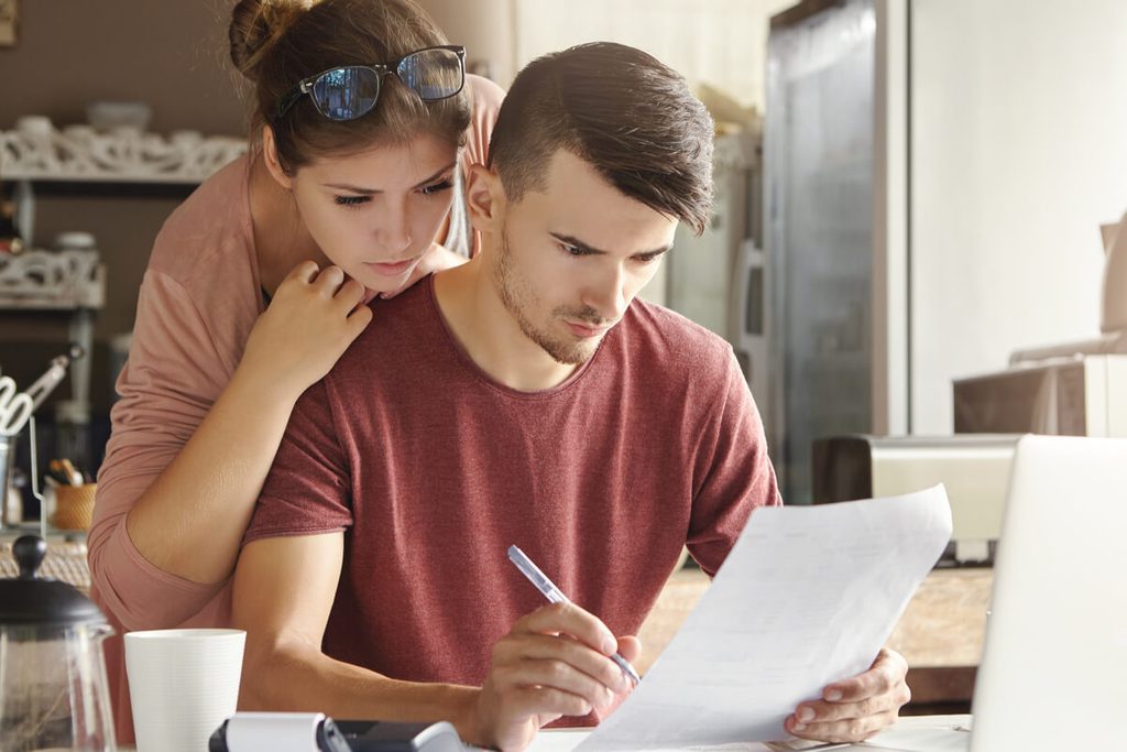 Couple organisant ses finances et la répartition des dépenses autour d'un carnet de comptes.