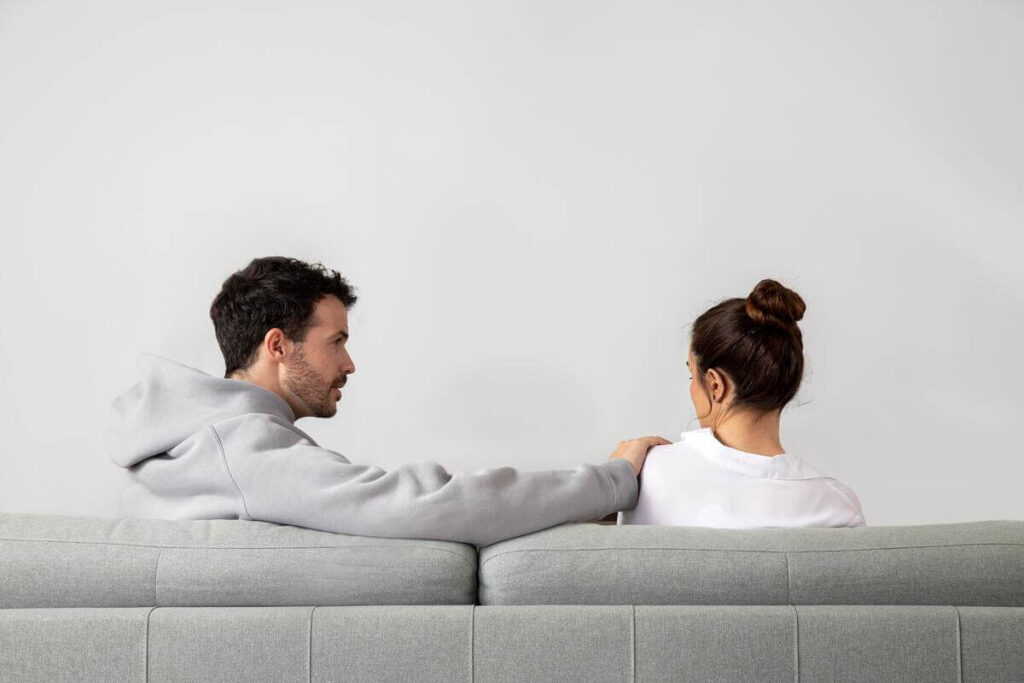 Il regarde les autres femmes avec insistance : significations et réactions 4 Couple échangeant au calme sur un canapé au sujet des limites relationnelles.
