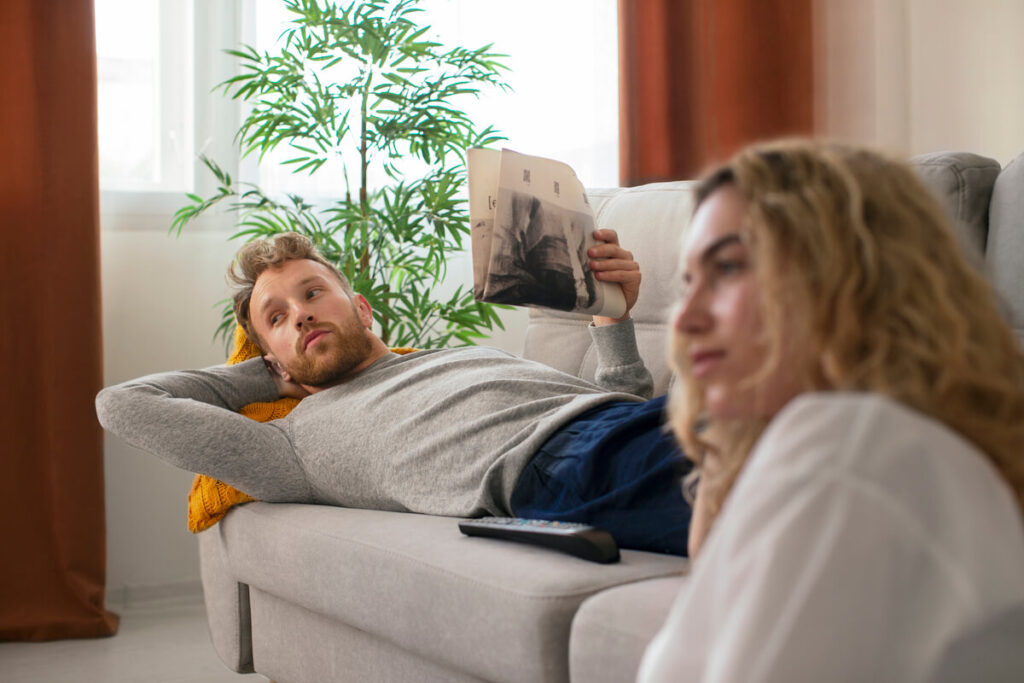 Il ne me soutient pas quand je vais mal : pourquoi et que faire 2 Femme pensive assise sur un canapé face à son partenaire distant et silencieux.
