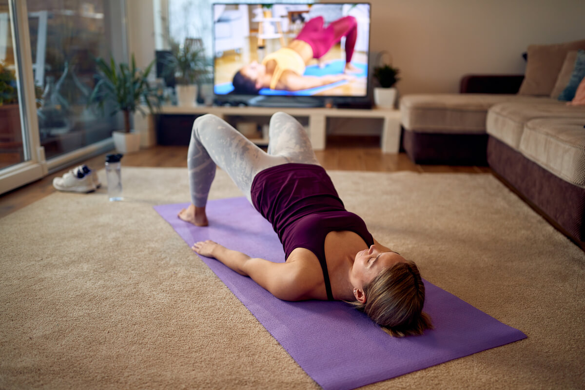 Femme réalisant des exercices de Kegel sur un tapis de sol pour renforcer son plancher pelvien.