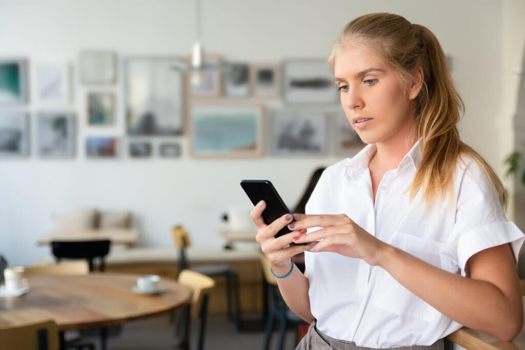 Il m'évite après m'avoir séduite : raisons et comportement à adopter 2 Femme anxieuse consultant son smartphone dans l'attente d'une réponse.