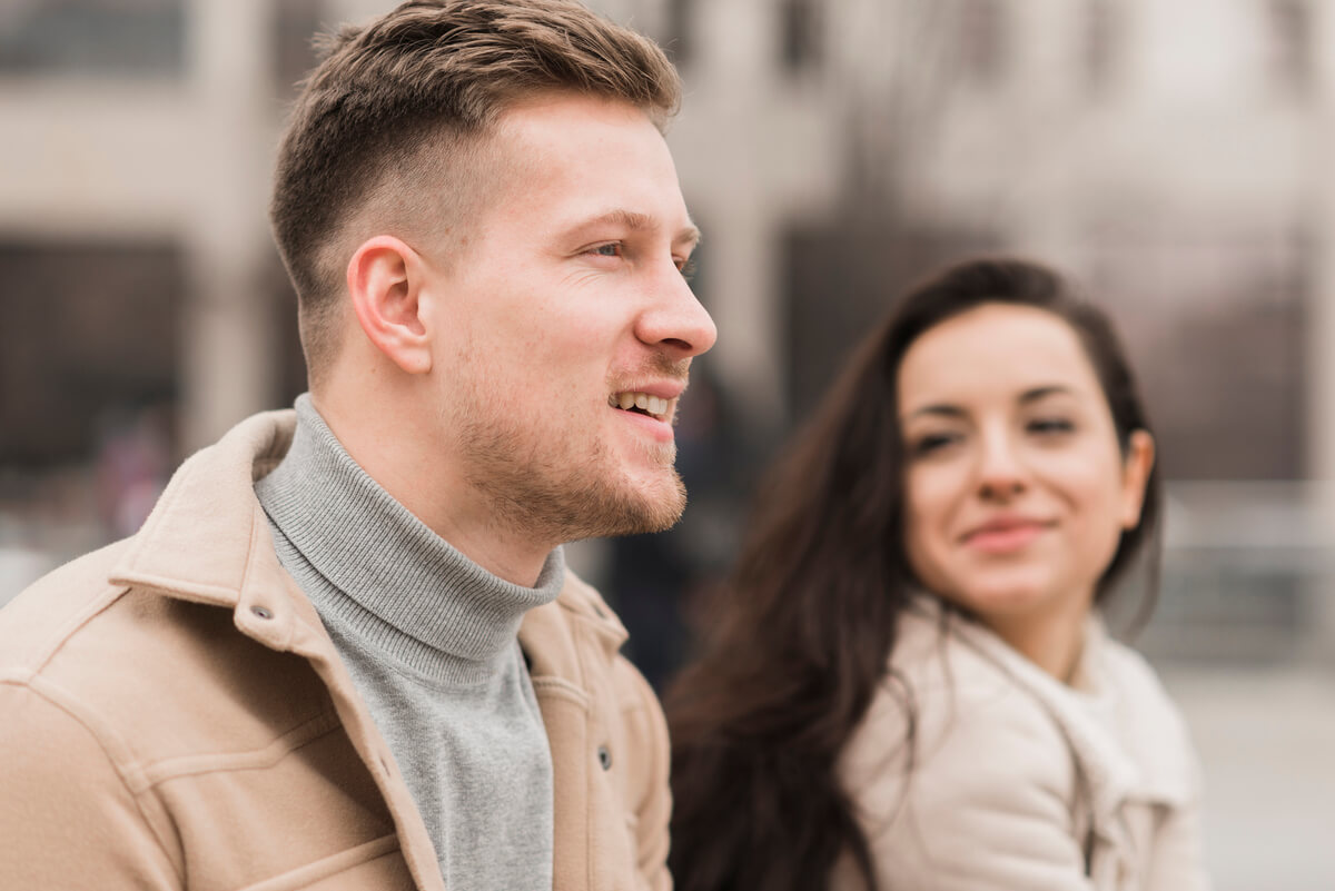 Homme en couple détournant le regard vers une autre femme dans la rue.