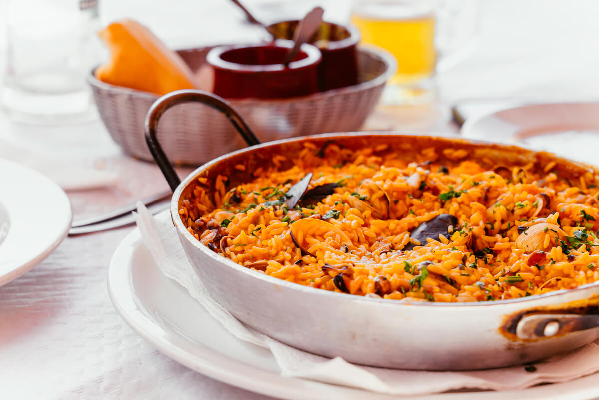 Cuisson d'une paella géante au feu de bois lors d'un repas de mariage champêtre.