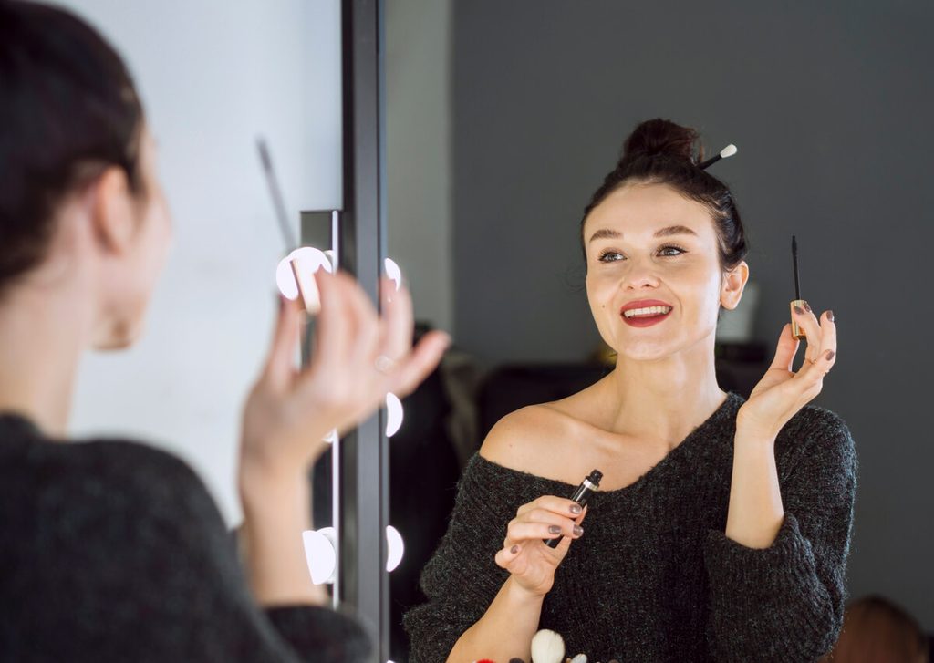 Regard dans le miroir lors du rituel quotidien de mise en beauté et de maquillage artistique.