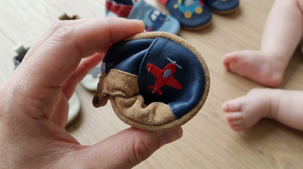Flexibilité d'une semelle en cuir suédé souple pliée entre les doigts pour tester la liberté du pied.