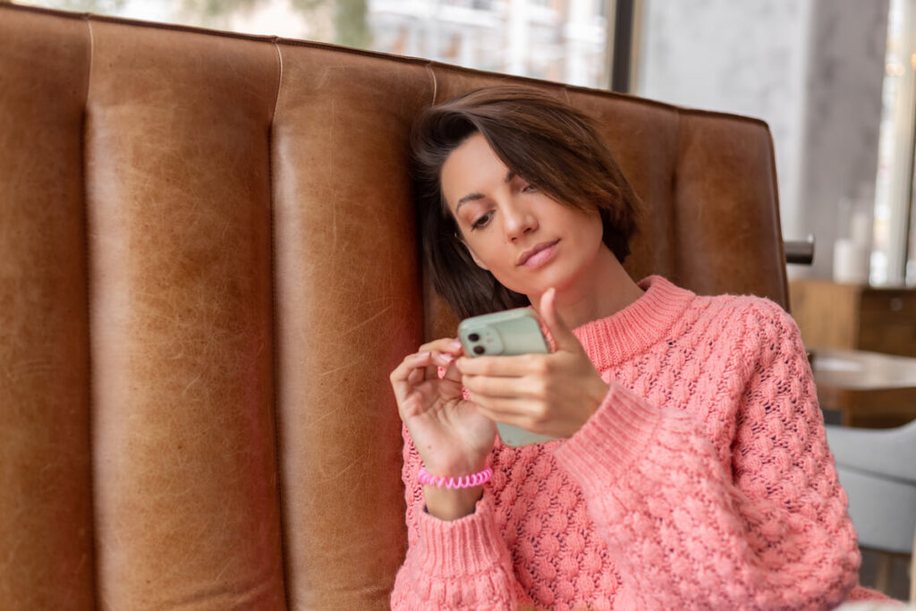Femme songeuse et blessée regardant son téléphone après une rupture sans retenue.