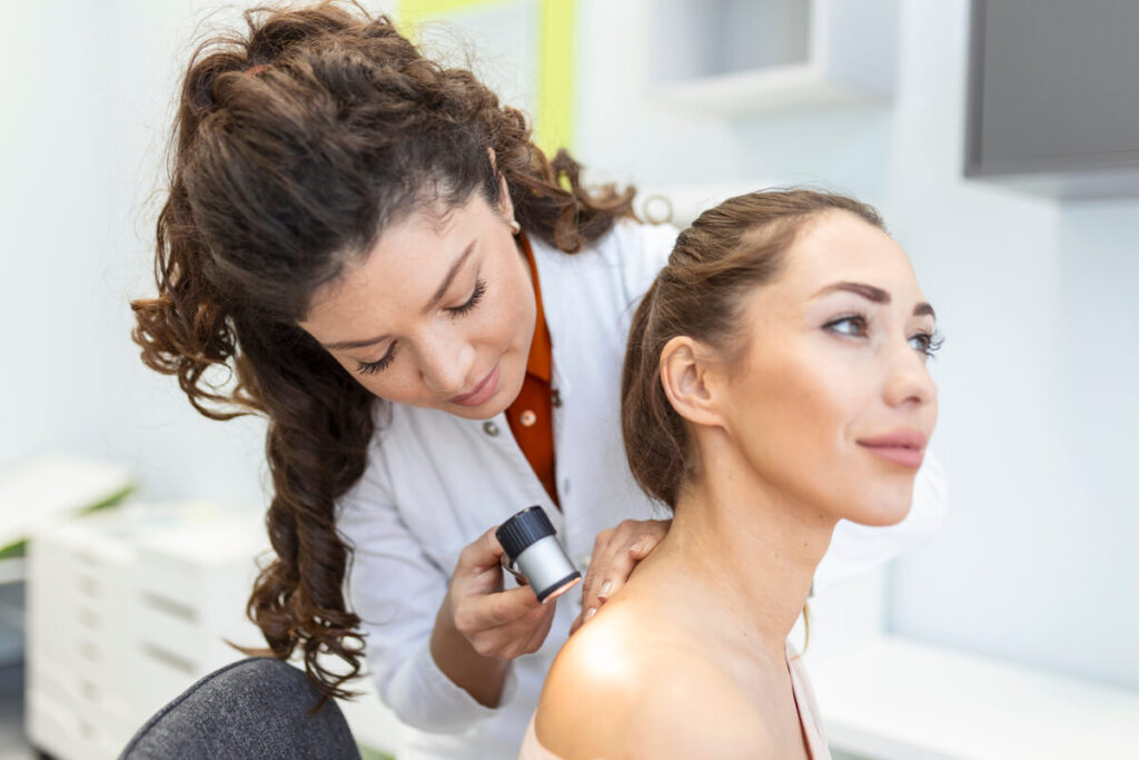 Grain de beauté sec qui tombe : est-ce dangereux ? 2 Dermatologue examinant une lésion cutanée brune et croûteuse à l'aide d'un dermatoscope.