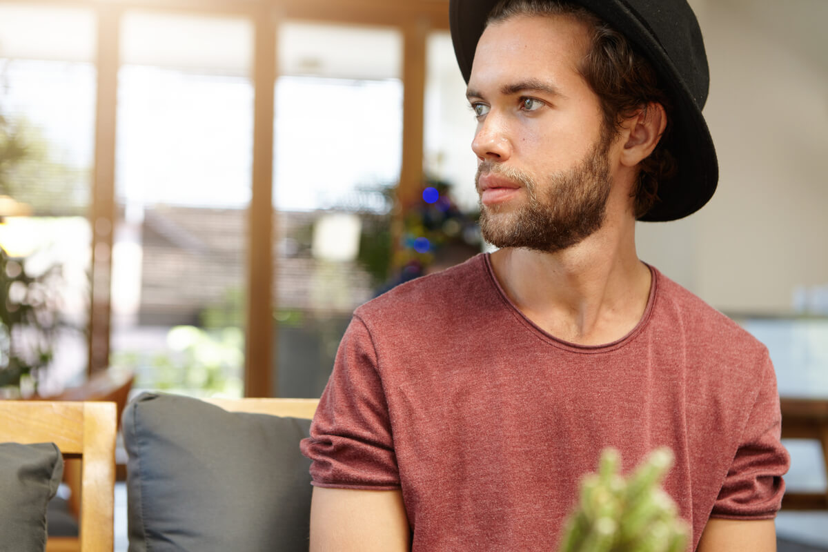 Homme échangeant un regard appuyé et discret à travers une pièce sans oser engager la conversation.