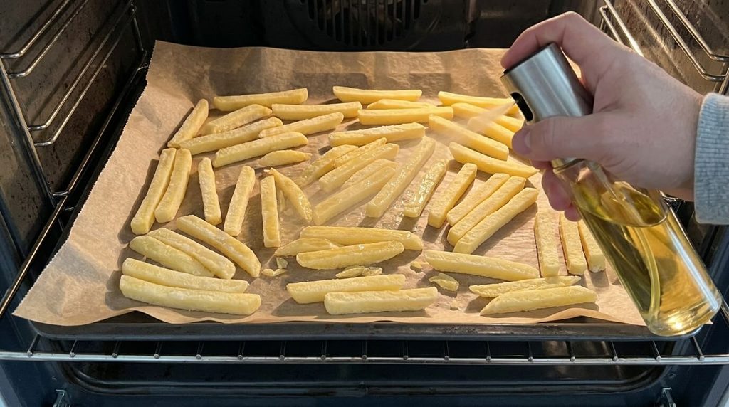 Huilage au vaporisateur sur des frites pour assurer une belle coloration dorée au four.